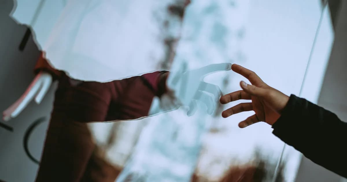 Manos intentando conectarse a través del reflejo de un cristal, simbolizando la búsqueda de conexión en las relaciones personales y el autoconocimiento.